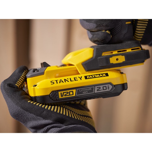 Foto van STANLEY SFMCD750D2K accu-boormachine met V20 2,0Ah lithium-ion batterij in gehandschoende handen.