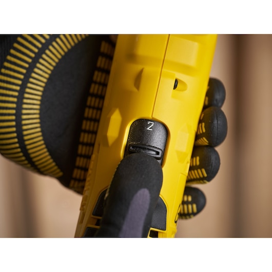 STANLEY SFMCD750D2K close-up van snelheidsselector, geel lichaam, handschoen drukt op schakelaar.