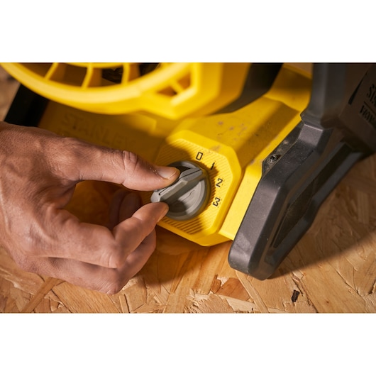 STANLEY SFMCE001B gros plan sur le bouton de réglage de vitesse du souffleur avec main ajustant les réglages.