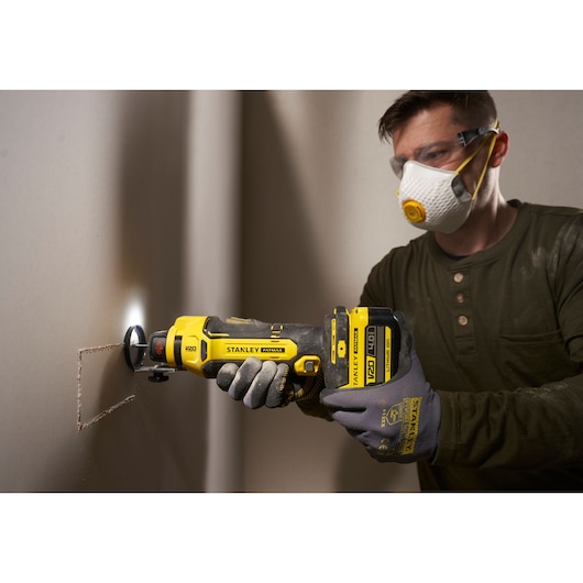 STANLEY SFMCE200B oscillatie-multitool zaagt gipsplaat, close-up zijaanzicht.