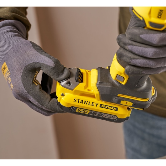 Foto van STANLEY SFMCE200B draadloos gereedschap met V20 FATMAX batterij, vastgehouden door gehandschoende handen.