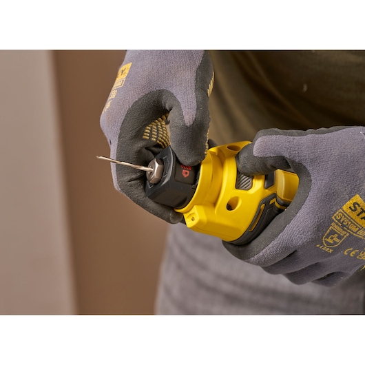 STANLEY SFMCE200B rotatiegereedschap in gehandschoende handen, close-up, gele en zwarte afwerking.