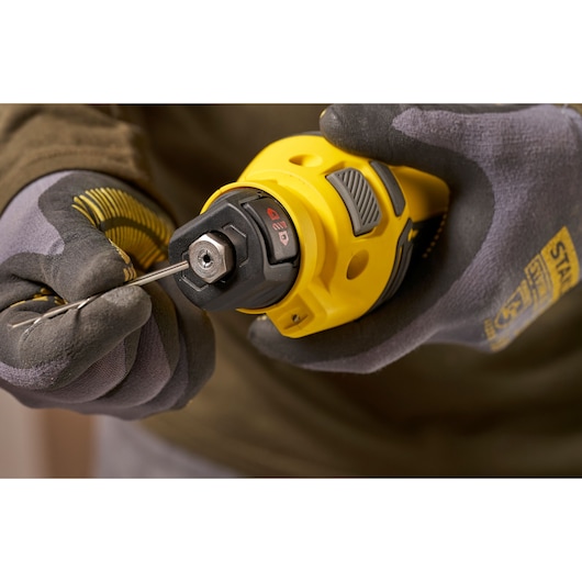 Stanley SFMCE200B rotatiegereedschap vastgehouden met handschoen, bit wordt geplaatst, close-up.