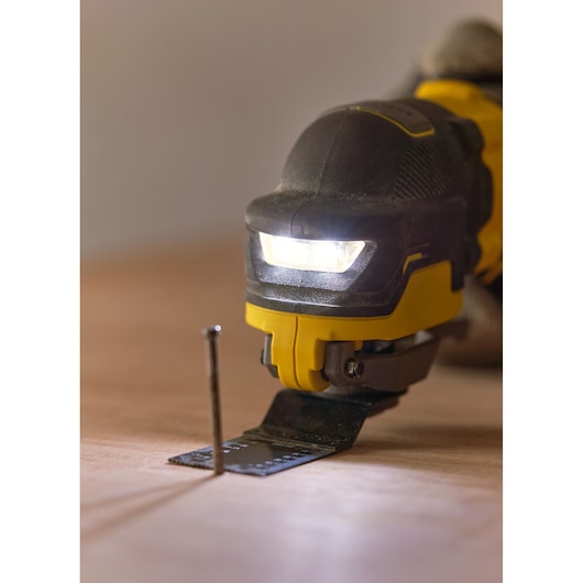 STANLEY SFMCE510B oscillerend gereedschap close-up met LED-licht, snijdt dicht bij een spijker op hout.