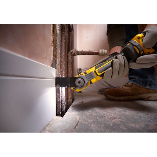 STANLEY SFMCE510B oscillerend multitool zaagt plint bij leidingen, close-up tijdens renovatie.