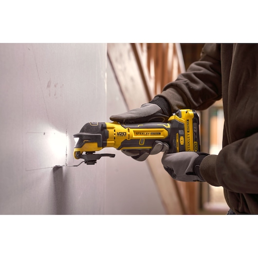 Stanley SFMCE510B oscillerend gereedschap snijdt gipsplaat, close-up in gebruik met handschoenen.