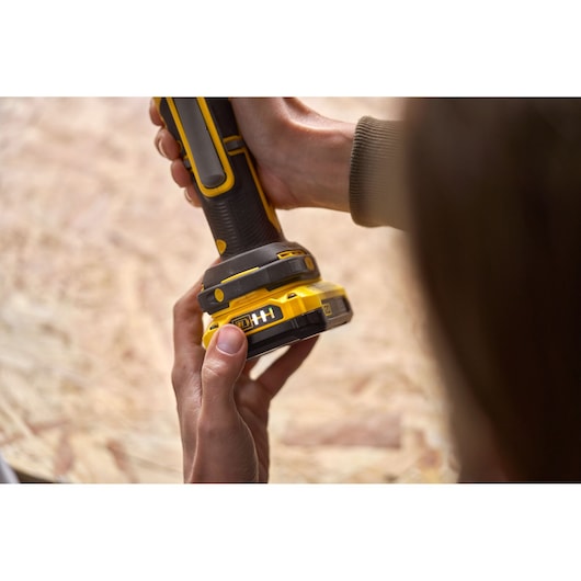 Foto van STANLEY SFMCE510B snoerloze schuurmachine in hand, close-up van handgreep en accu.