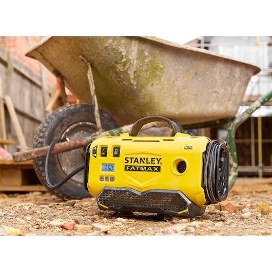 STANLEY SFMCE520B draagbare gele FATMAX V20 pomp op een bouwplaats met een kruiwagen.
