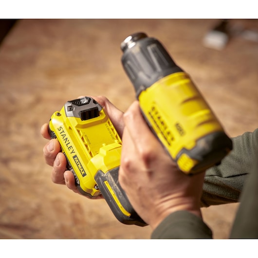 Photo de l'outil sans fil STANLEY SFMCE530B en utilisation, jaune et noir, gros plan de mains tenant l'outil.