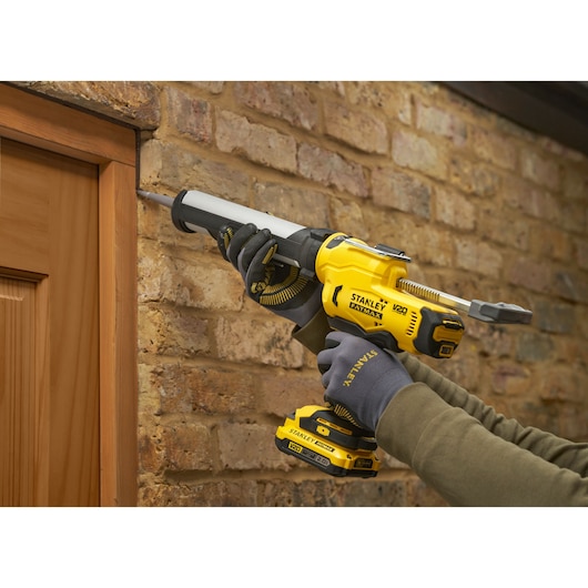 STANLEY SFMCE600B pistolet à calfeutrer utilisé pour sceller autour d’un cadre de porte en bois contre un mur en briques.