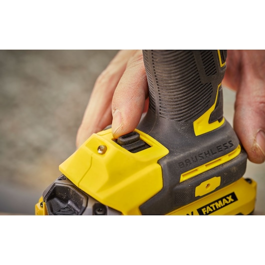 STANLEY SFMCF920B perceuse brushless en gros plan, poignée jaune et noire, main appuyant sur bouton.