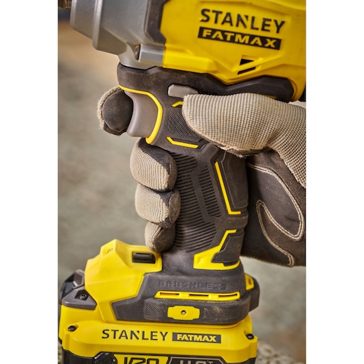 Photo du tournevis à percussion STANLEY SFMCF920B tenu par une main gantée, poignée ergonomique jaune et noire.