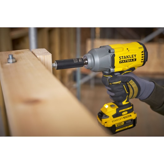 Foto van STANLEY SFMCF940M1 draadloze slagschroevendraaier die een bout in houten balken aandraait, close-up.