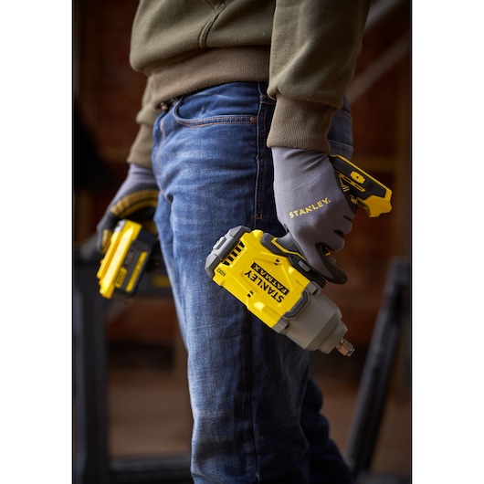 Foto van STANLEY SFMCF940M1 accu slagschroevendraaier in een gehandschoende hand, geel-grijs design.
