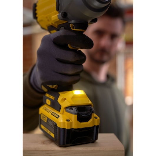 Foto van de STANLEY SFMCF940M1 slagschroevendraaier in gebruik, geel-zwart ontwerp, close-up van gehandschoende hand.