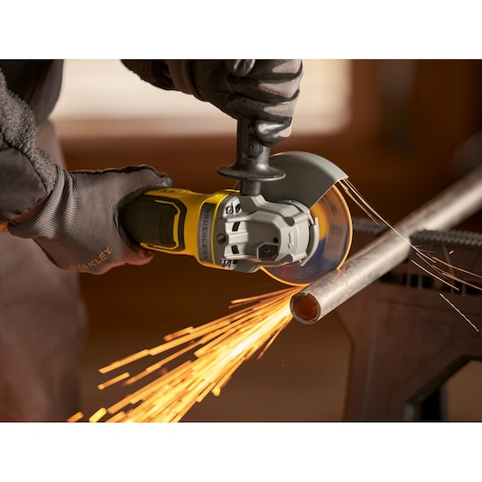 Stanley SFMCG700M2K slijper snijdt metalen buis met vonken, close-up actiebeeld.