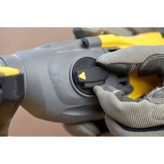 Close-up foto van de STANLEY SFMCH900B boorhamer keuzeschakelaar met gehandschoende hand.