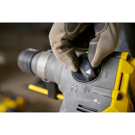Close-up foto van STANLEY SFMCH910R1T boorhamer modusknop ingesteld met een gehandschoende hand.