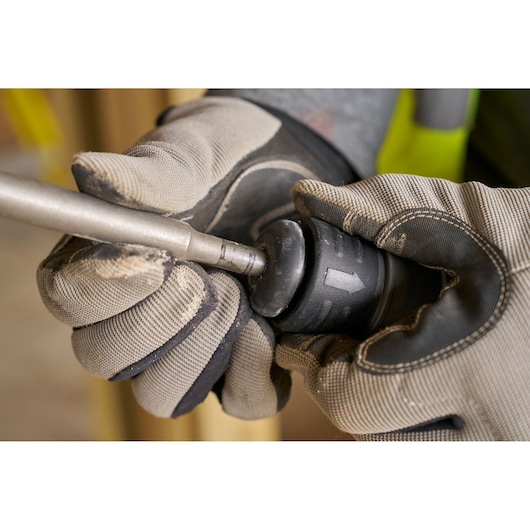 Foto van STANLEY SFMCH910R1T roterende hamer boorwissel, close-up met handschoenen, zijaanzicht.