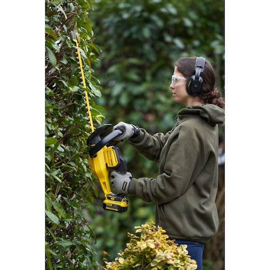 STANLEY SFMCHT855M1 taille-haie sans fil en utilisation extérieure, design jaune et noir, vue latérale.