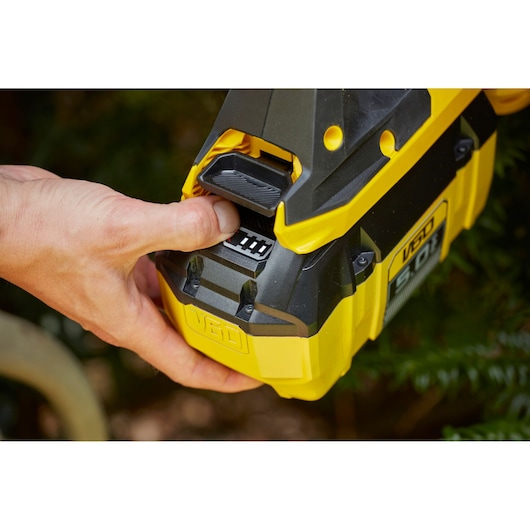 STANLEY SFMCHTB866B batterie en gros plan avec une main appuyant sur le bouton, outil jaune et noir.