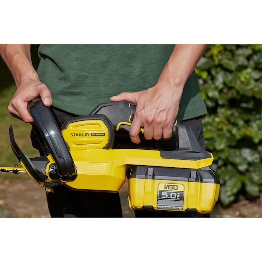 Photo du taille-haie STANLEY SFMCHTB866B jaune et noir, tenu par une personne en extérieur.