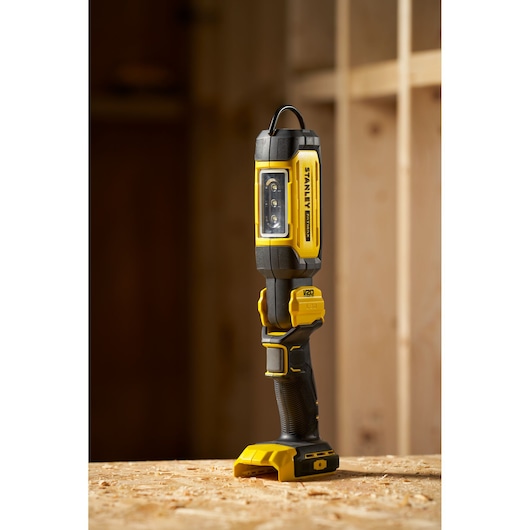 STANLEY SFMCL050B 18V FATMAX V20 Pivot Light, geel-zwarte LED-werklamp rechtop op houten oppervlak.
