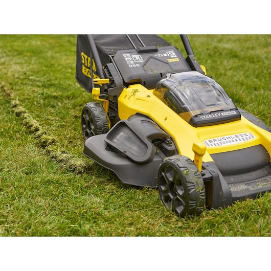 Stanley SFMCMW2651M gele en zwarte brushless grasmaaier close-up op gras, zijaanzicht.