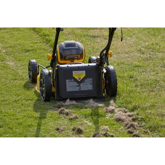Foto van STANLEY SFMCMW2653B grasmaaier achteraanzicht op groen gras met mulch en waarschuwingslabel zichtbaar.