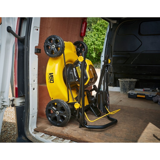 STANLEY SFMCMW2653B grasmaaier opgevouwen en rechtop opgeslagen in een bestelwagen, geel met zwart ontwerp.