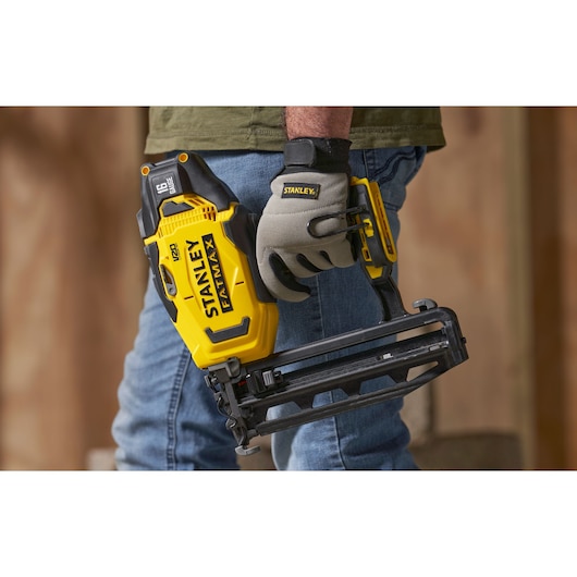 Foto van een persoon met een gele en zwarte STANLEY SFMCN616B snoerloze tacker, gebruikt voor constructiewerk.