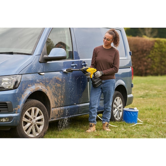 STANLEY SFMCPC93B draagbare washer gebruikt om een modderige blauwe bestelwagen buiten schoon te maken.