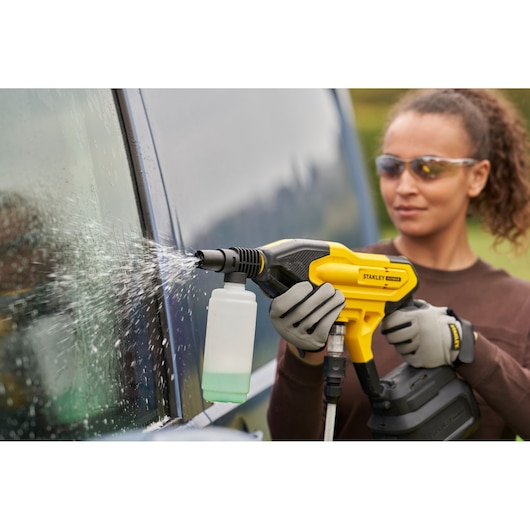 Stanley SFMCPC93B draadloze reiniger spuit water op een auto ruit, close-up, buiten.