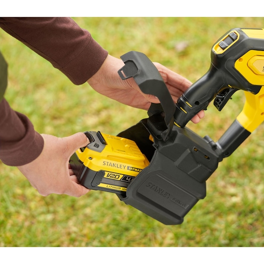Stanley SFMCPC93B batterij wordt geplaatst in gele powertool buiten, close-up.
