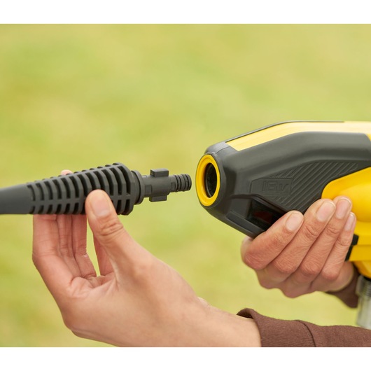 STANLEY SFMCPC93M1 close-up van hogedrukreiniger mondstuk aansluiting, geel-zwart gereedschap in hand.