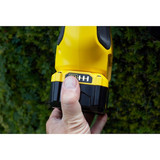 STANLEY SFMCPH845M1 draadloos gereedschap batterij in hand, close-up met groene achtergrond.