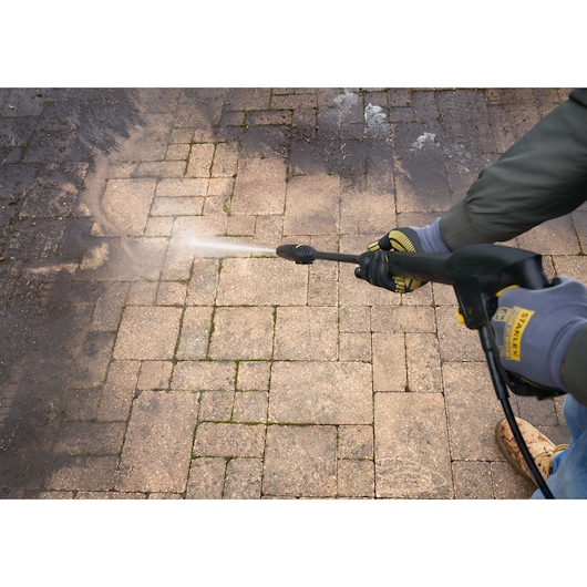 Stanley SFMCPW1500B hogedrukreiniger reinigt een vuile stenen patio, close-up.