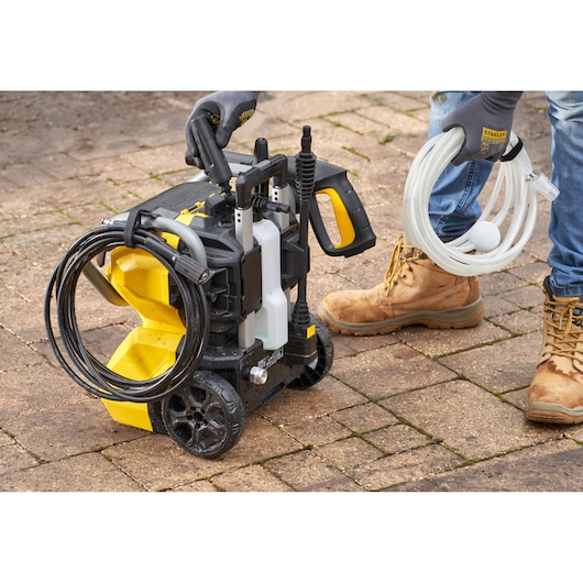 STANLEY SFMCPW1500B hogedrukreiniger met slang en accessoires, foto van product op buitenbestrating.