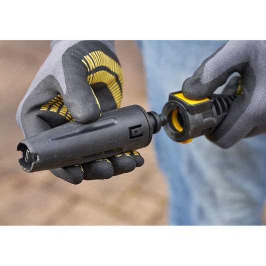 STANLEY SFMCPW1500B slangconnector vastgehouden door gehandschoende handen, close-up buiten.