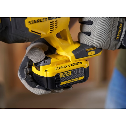 Photo de l'outil électrique STANLEY SFMCS300B avec batterie V20 4.0Ah lithium-ion tenue par des mains gantées.