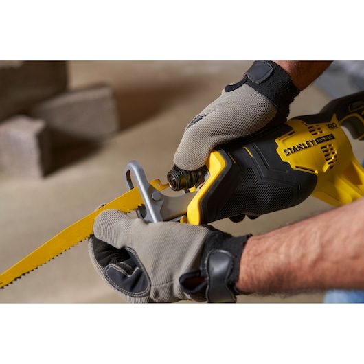 STANLEY SFMCS300B scie sabre tenue par des mains gantées, jaune et noir vue de côté rapprochée.