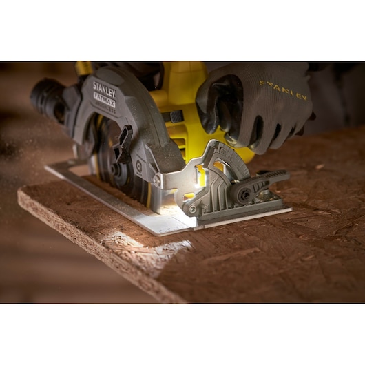 Scie circulaire STANLEY SFMCS550B coupant du bois, vue rapprochée, main gantée utilisant l'outil.