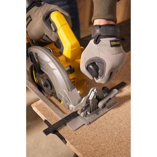 STANLEY SFMCS550B scie circulaire vue rapprochée, poignée jaune, coupe du bois, opérateur avec des gants.
