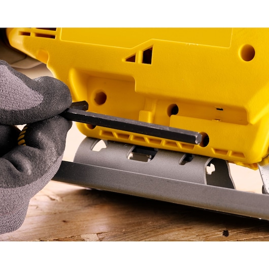 STANLEY SFMCS600B scie sauteuse ajustée avec clé hexagonale, photo gros plan sur corps jaune et base grise.