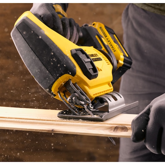 STANLEY SFMCS600B scie sauteuse coupant du bois, vue rapprochée, outil électrique jaune et noir en action.