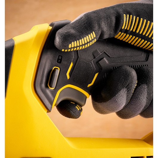 Photo de la poignée de l'outil STANLEY SFMCS600B, vue rapprochée, noir et jaune, tenue par une main gantée.