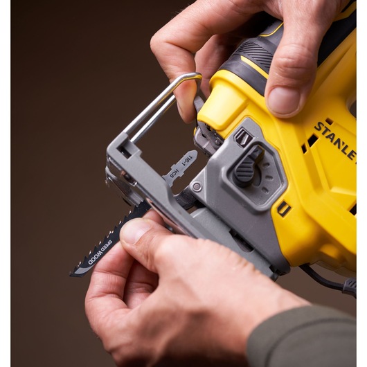 STANLEY SFMCS650B scie sauteuse brushless 18V vue rapprochée, montage de la lame, corps jaune et noir, tenue à la main.