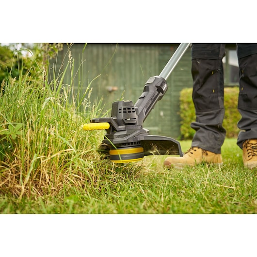 STANLEY SFMCST925M1 coupe-bordure en utilisation, gros plan de la tête de coupe taillant de l’herbe haute en extérieur.