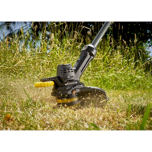 Taille-herbe STANLEY SFMCST925M1 en gros plan coupant de l'herbe haute en extérieur.