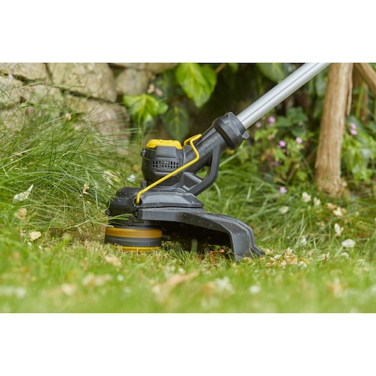 STANLEY SFMCST933B grastrimmer close-up in gebruik op gras, zwart met gele accenten.